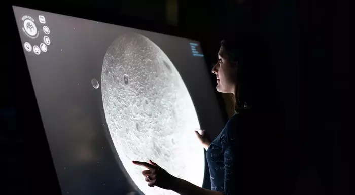 A woman looking at an image of the moon